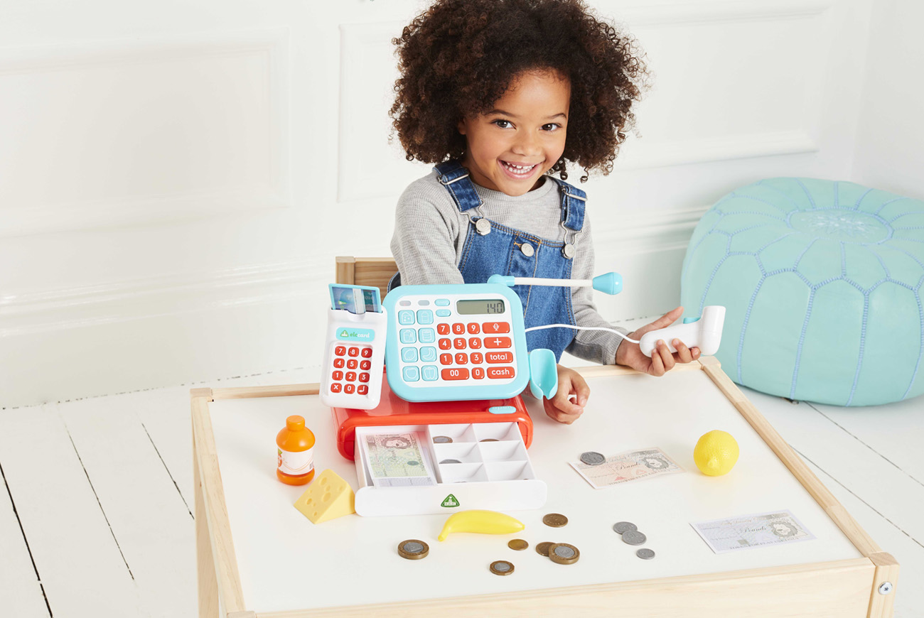 Child playing shops with toy till